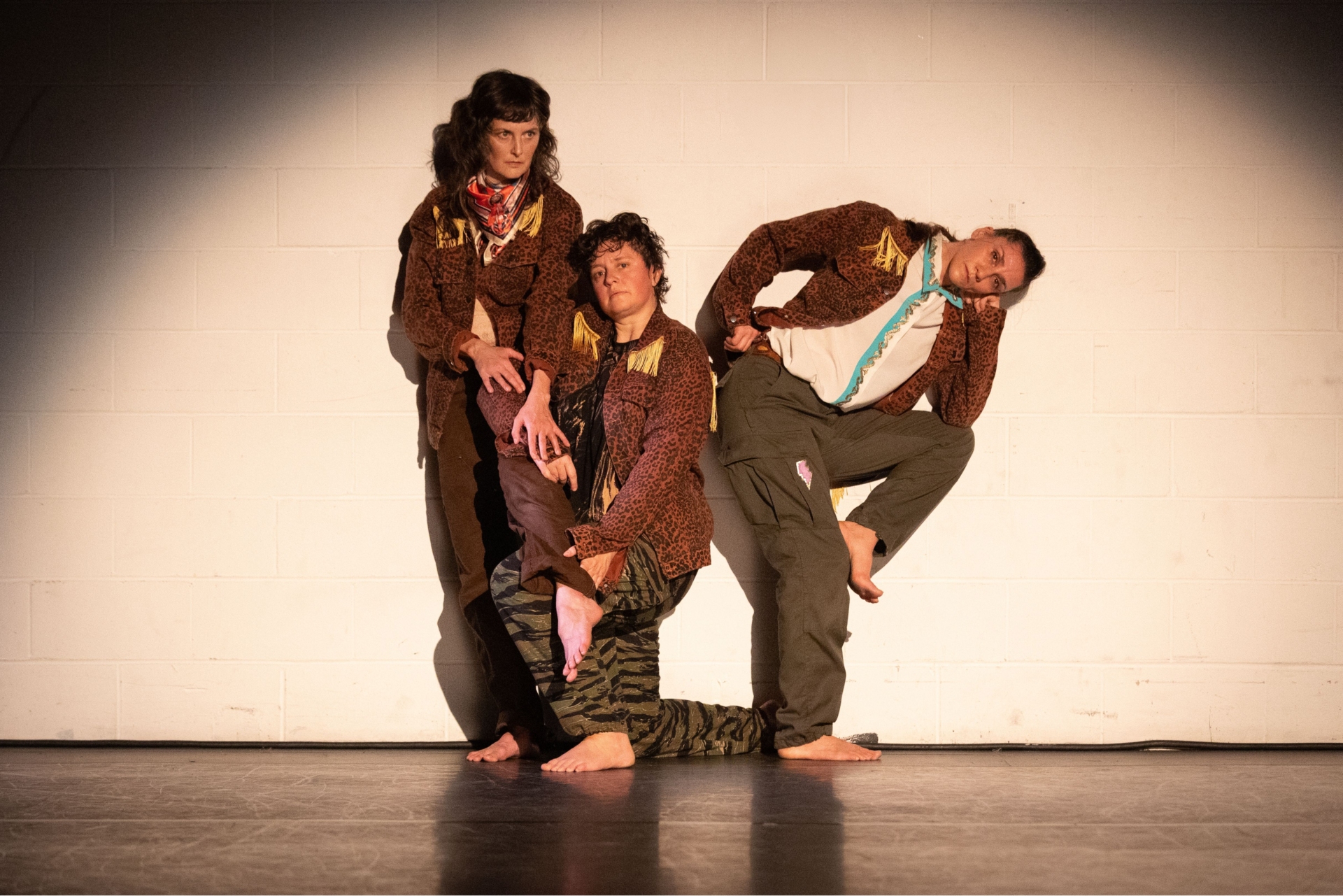 Trois interprètes sont au centre de la photo. La personne de gauche est debout, celle du centre à genoux et celle de droite accote son coude sur son genoux.