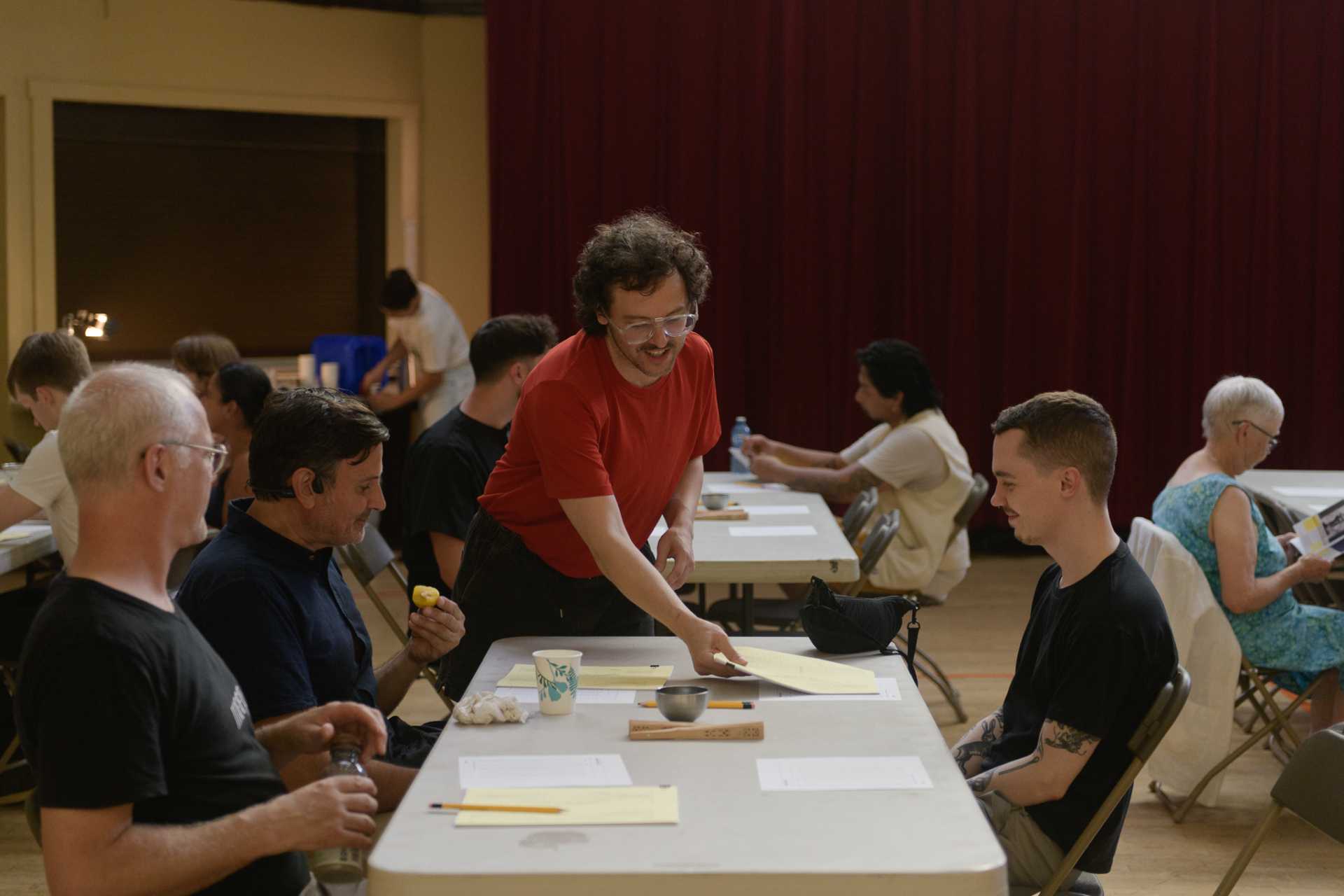 Evan Webber distribue des questionnaires à une table de 3 participants.