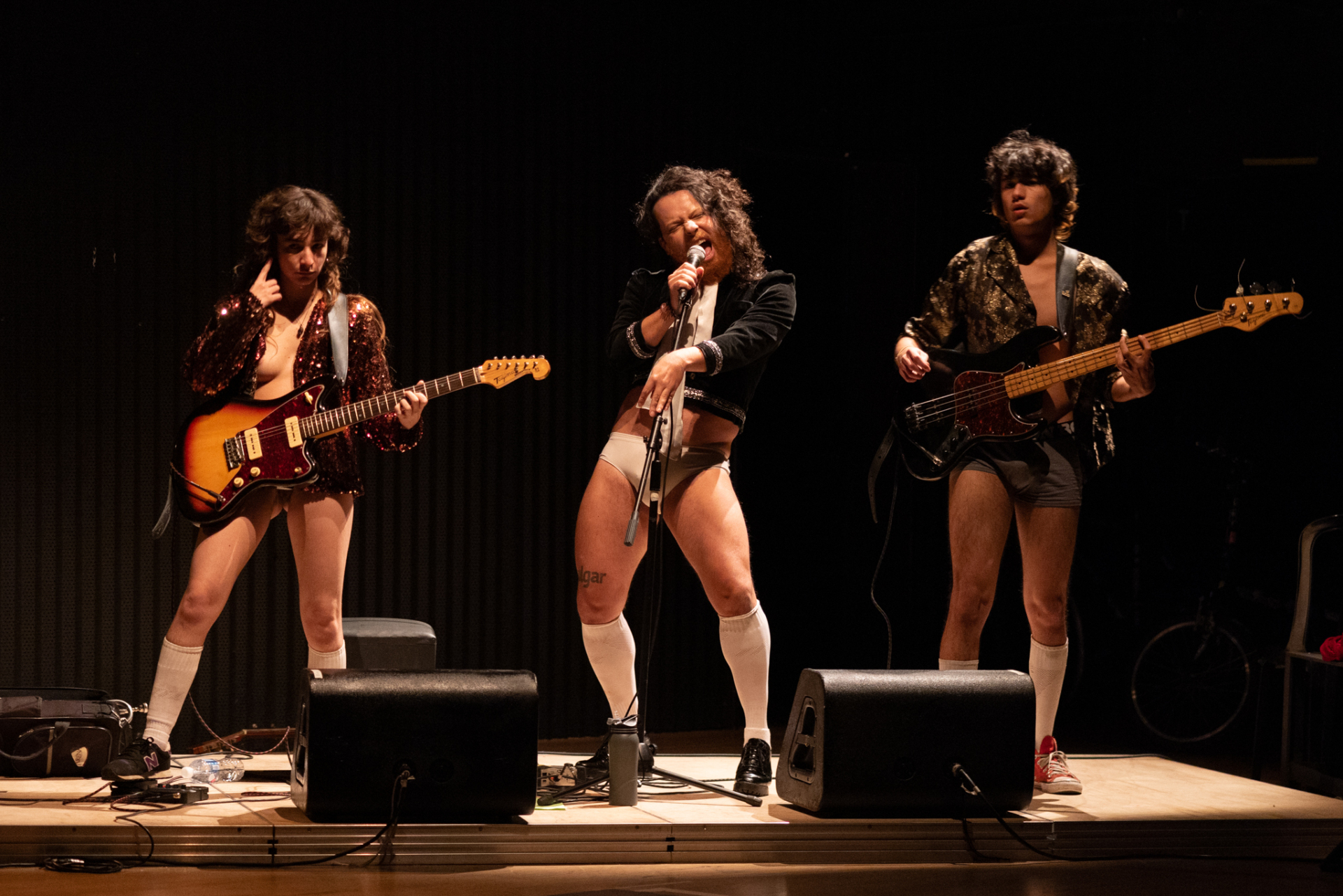 Un groupe de musique rock joue en slip sur scène.