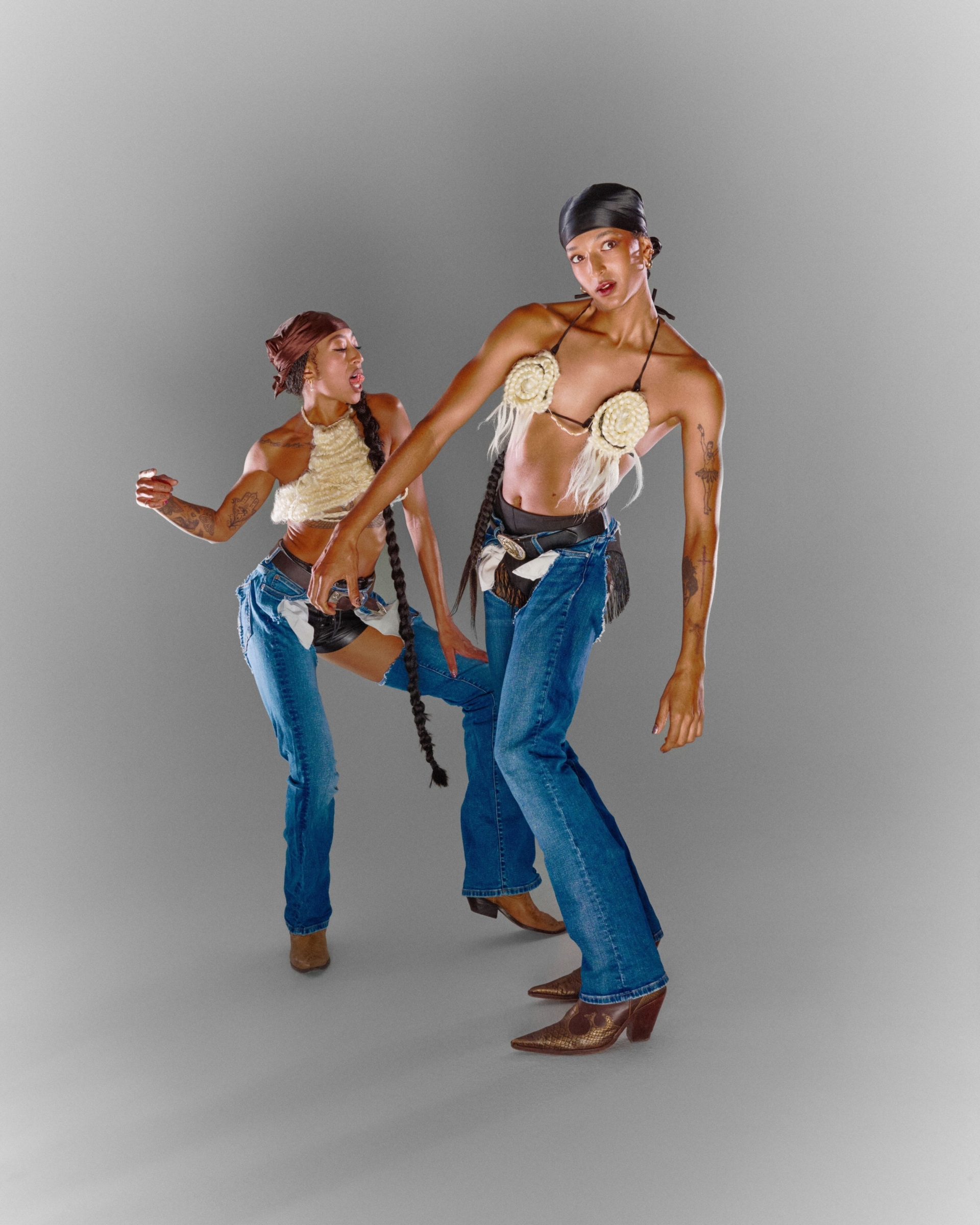 Posant l'une devant l'autre, Stacey et Satinée mettent en valeur leurs longues tresses et leurs habits de cowboy : short en cuir noir, chaps en jeans, bottes de cowboy et haut en corde blanche.