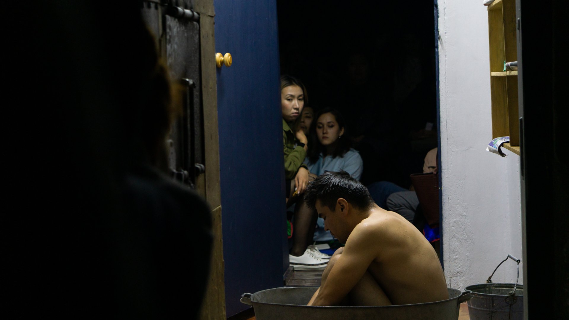 Un homme est nu dans une bassine d'eau au milieu d'un corridor.