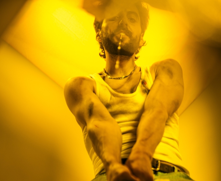 Un personnage sous une lumière jaune en débardeur blanc