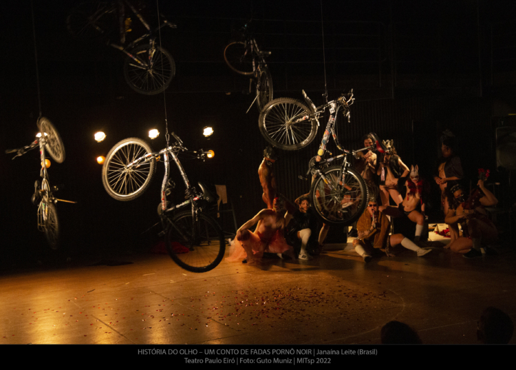 Des vélos sont suspendus au plafond. Un groupe de personnes se trouve derrière eux.