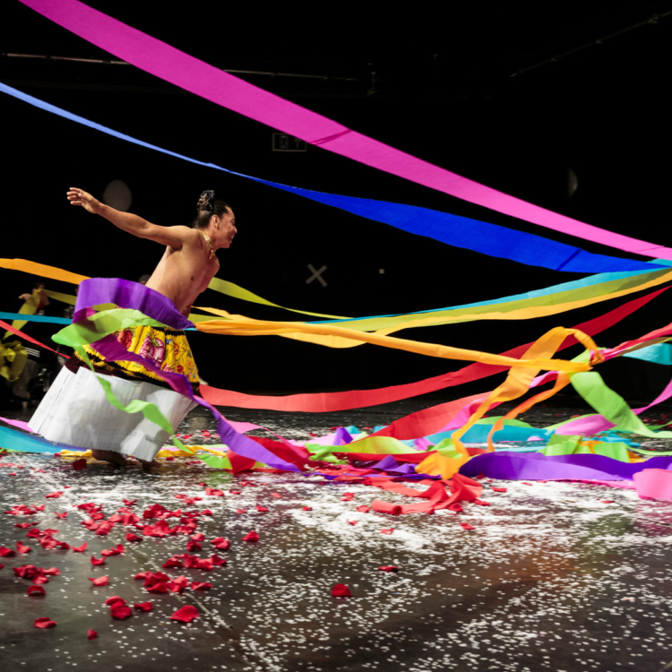 Lukas Avendano est entouré de grands rubans multicolores qui volent autour de lui sur la scène.
