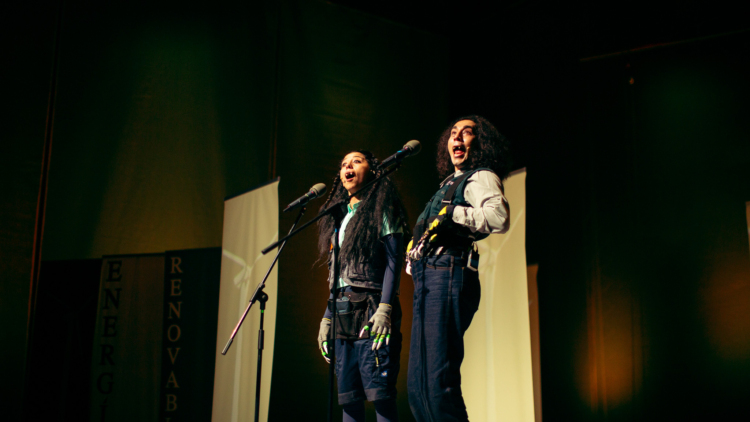 Deux personnages avec des griffes aux doigts, vêtus de blue jeans, de chemise de travailleurs, chantent devant des micros