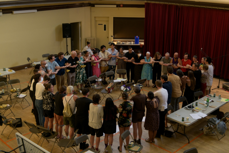 Les participants se tiennent bras dessus bras dessous autour d'une cercle de chaises.