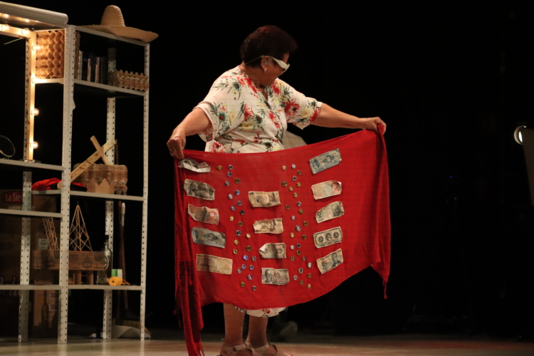 Josefina Orlaineta holds up a red cloth with banknotes attached to it.