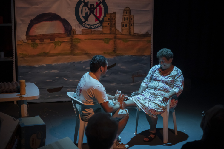 Anacarsis Ramos and his mother are sitting on white plastic chairs with blue lighting