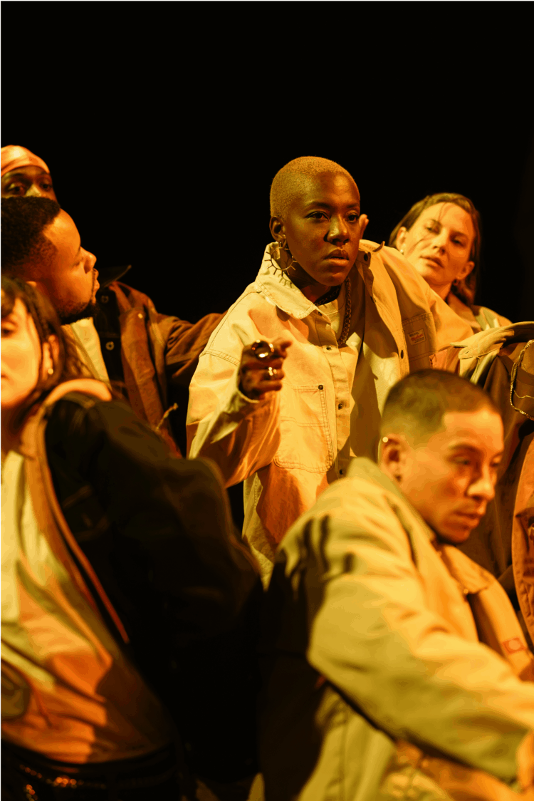 A performer, in the centre of the group, stands out as the group moves downwards.