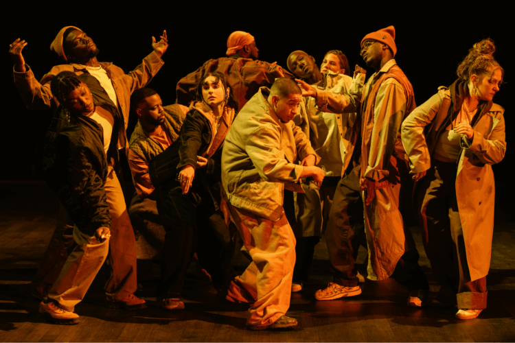 In a confined space, ten dancers move under orange lighting.