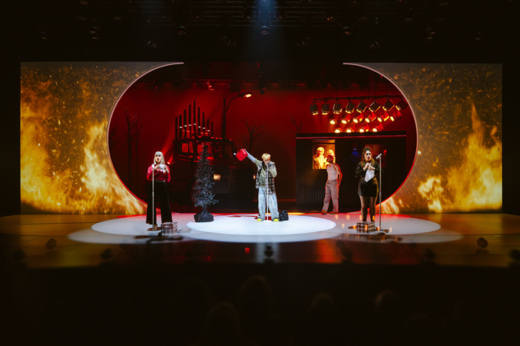 On stage, we see a truck and the front of a house in a large opening, with side panels simulating a fire. In front of it are four characters from the novel Querelle de Roberval addressing the audience.