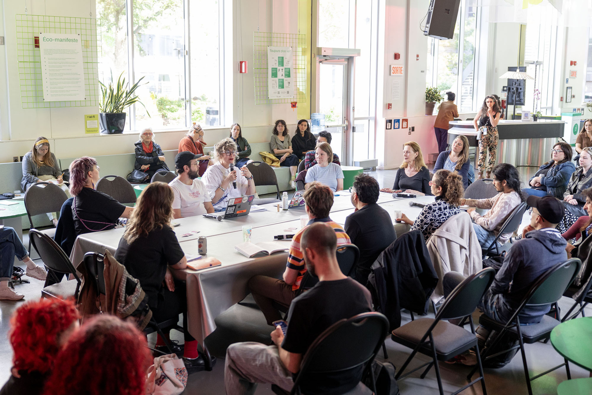 Plusieurs personnes assises autour d'une table sont en discussion au Quartier général du FTA.