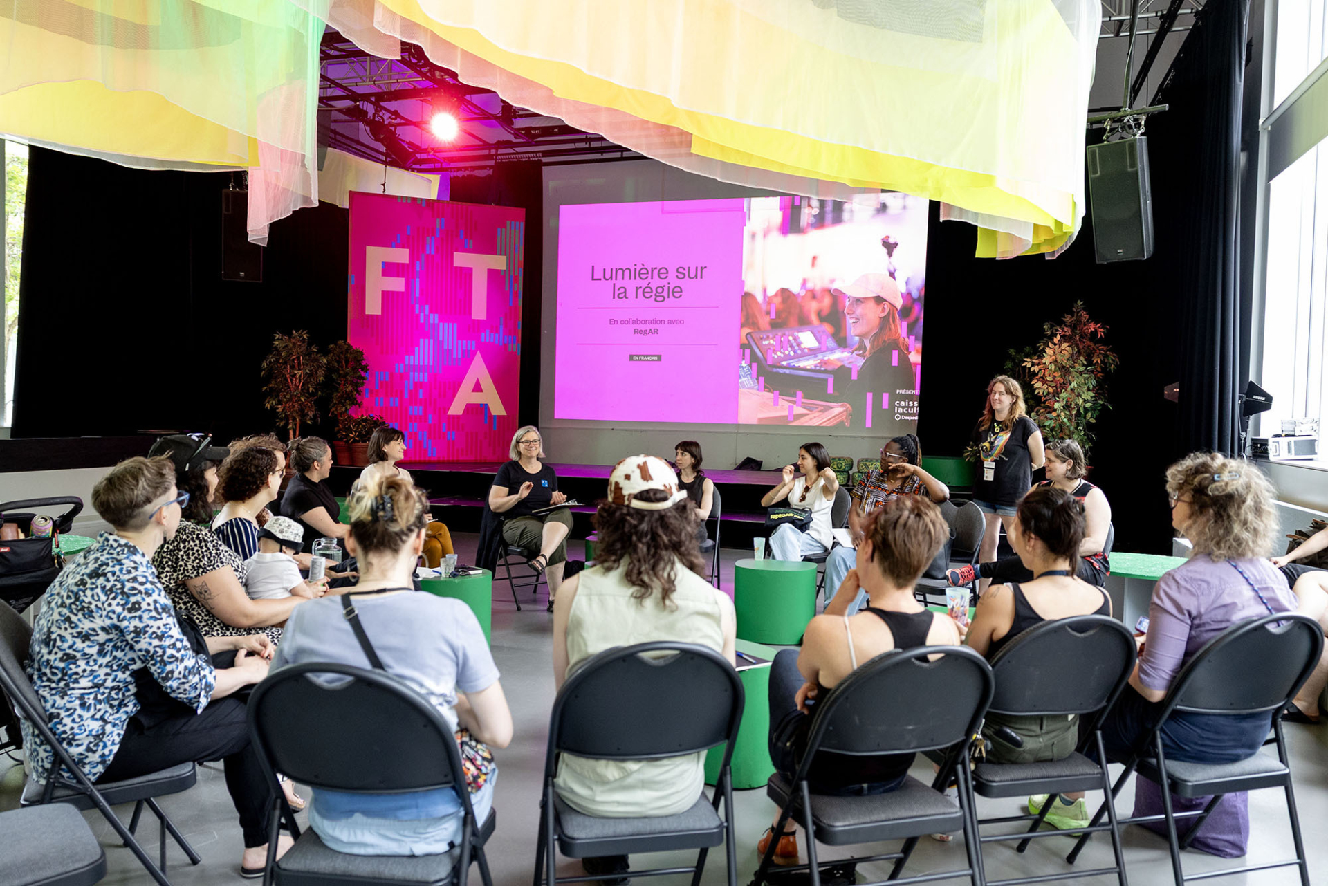 Plusieurs personnes assises en cercle font face à un panel de régisseurs lors de la présentation de Lumière sur la régie du FTA 2025.