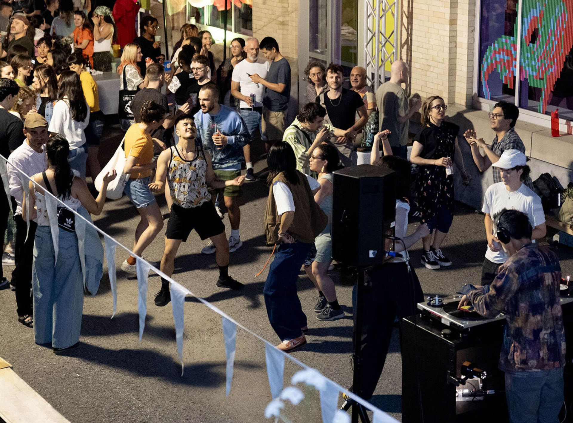 People are dancing outside in front of the FTA headquarters during a DJ set.