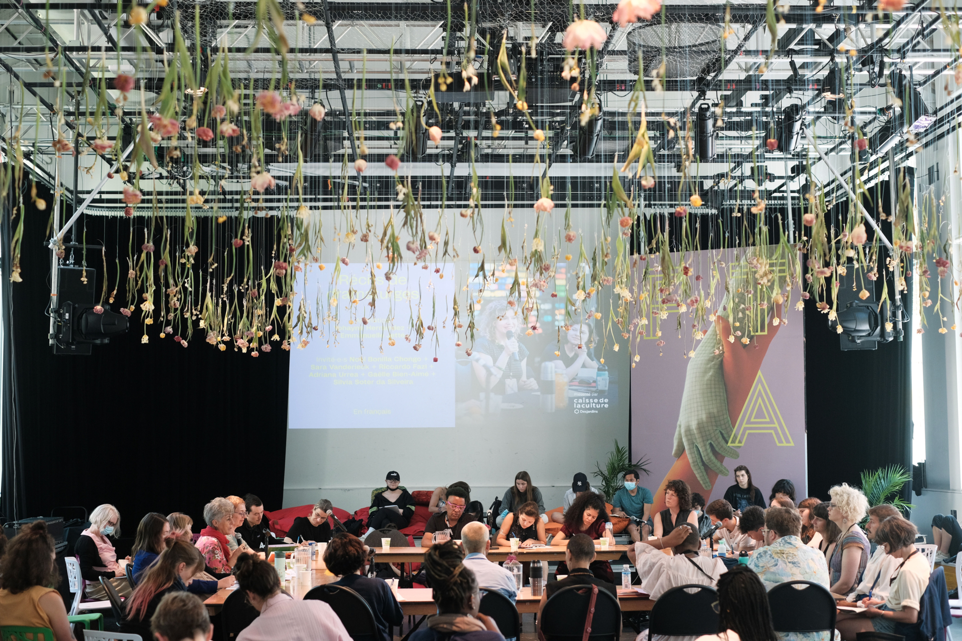 Des personnes sont attablées en cercle dans une grande salle.