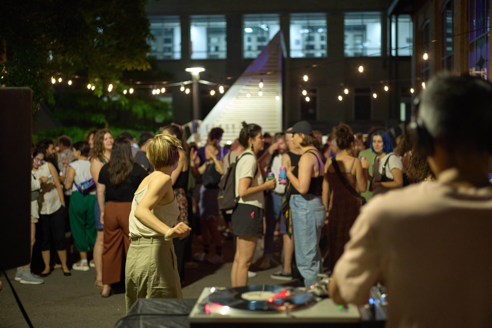 People are partying in front of the FTA headquarters, and a DJ is shown from behind in the foreground.