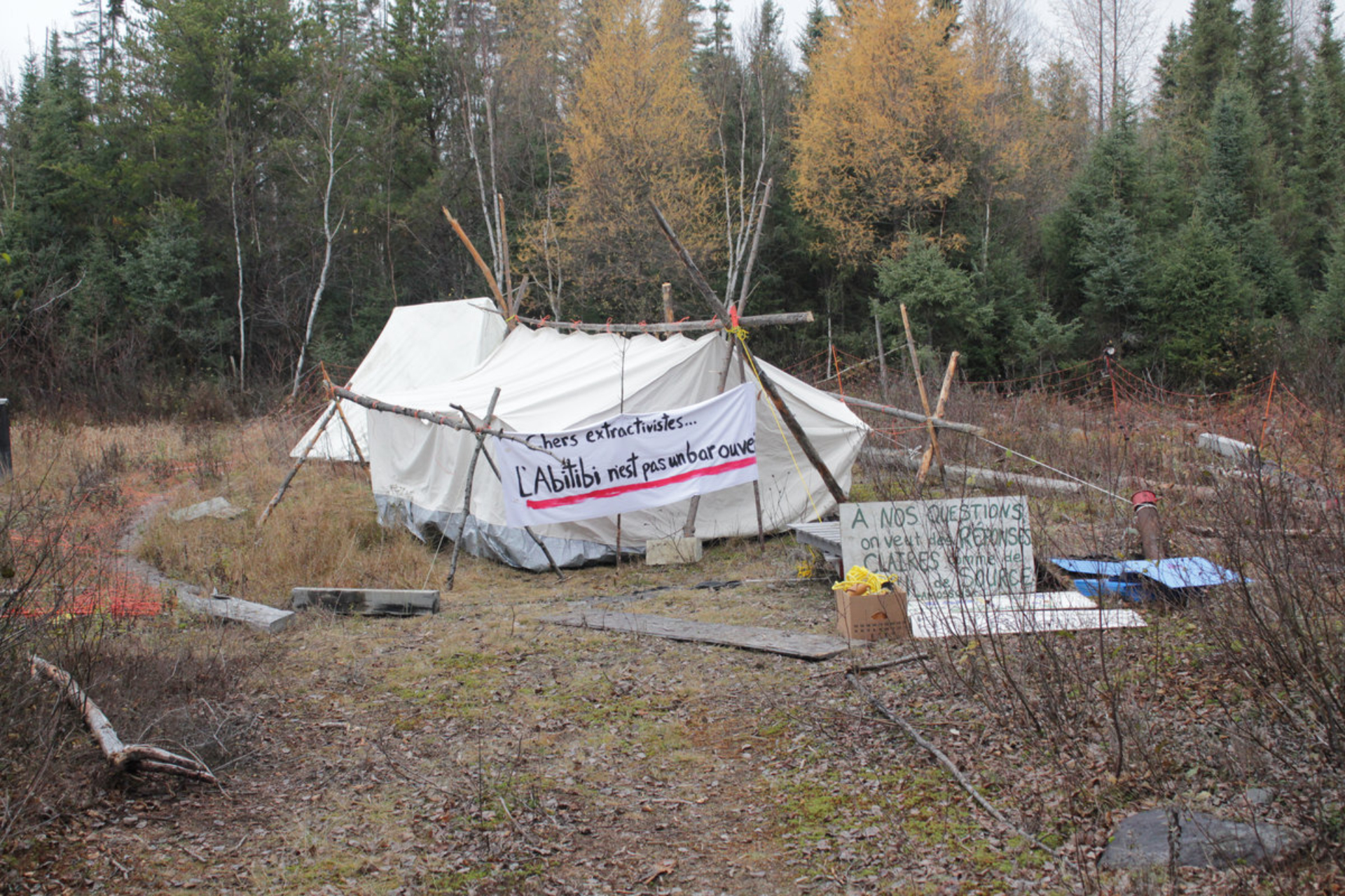 Photo d'une tente de campement dans la nature avec des banderoles contre l'extractivisme.