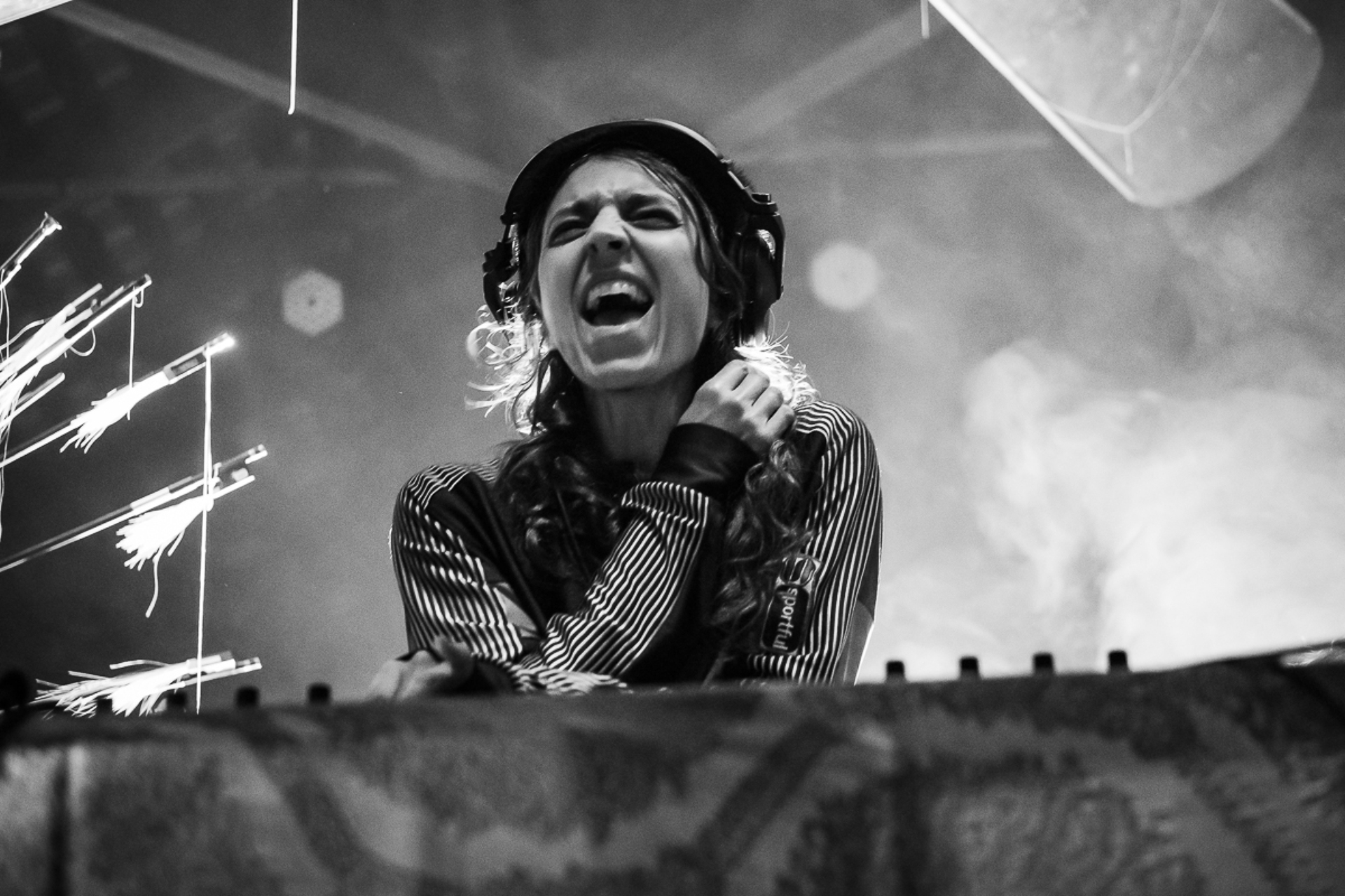 In a black-and-white photo, DJ Julie D is behind the turntables with headphones on and her mouth open as if she were singing.
