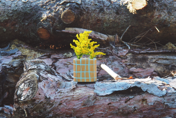 Un vase en bois avec des lignes bleues en résine est posé sur un tronc d'arbre.